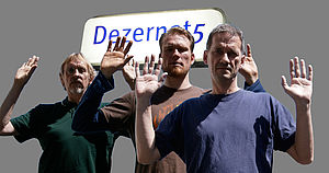 Drei Männer stehen mit erhobenen Händen vor einem leuchtenden Schild mit der Aufschrift "Dezernat 5".