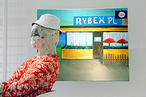 Eine Puppe schaut in den Ausstellungsraum.