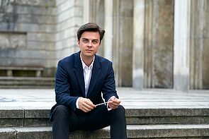 Eine Musiker sitzt auf einer Treppe.