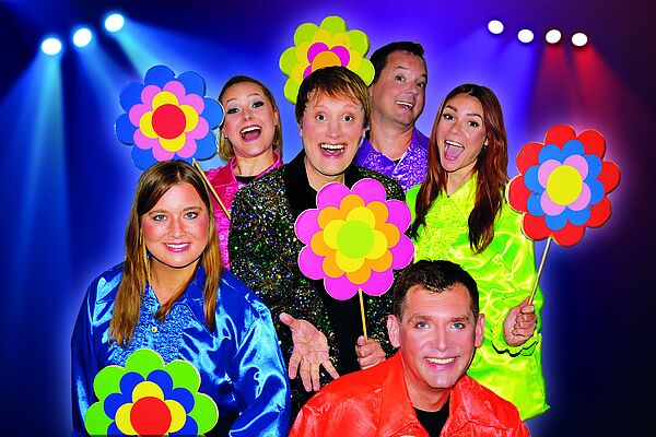 Sechs Schauspielerinnen und Schauspieler in bunter Kleidung und grellen Farben.