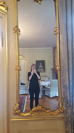 Ein raumhoher, goldener Spiegel. Darin spiegel sich Susanne Gabler, wie sie den Spiegel fotografiert. 