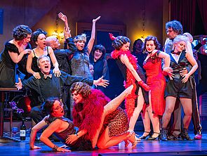 Trubel auf der Bühne. Menschen tanzen und feiern.