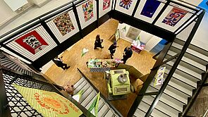 In einem Treppenhaus hängen Kunstwerke.