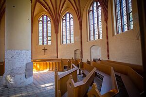 Eine Kirche von innen. Bänke stehen halbrund an einer Wand.