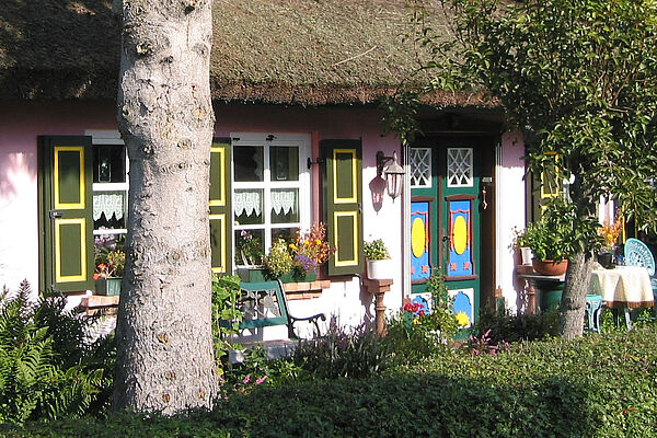 Ein Reetdach-Haus mit einer bunten Haustür.