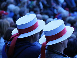 Zwei Zuschauerinnen und Zuschauer mit Hüten.