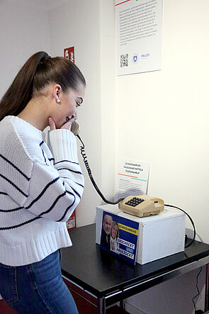 Eine junge Frau telefoniert mit einem alten Telefon.