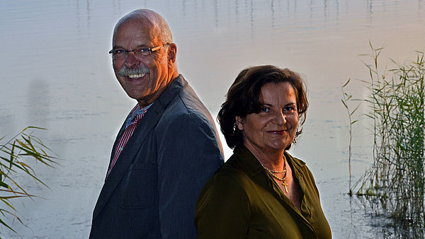 Susanne Gilbert und Uwe Driest stehen Rücken an Rücken in einem Raum. 