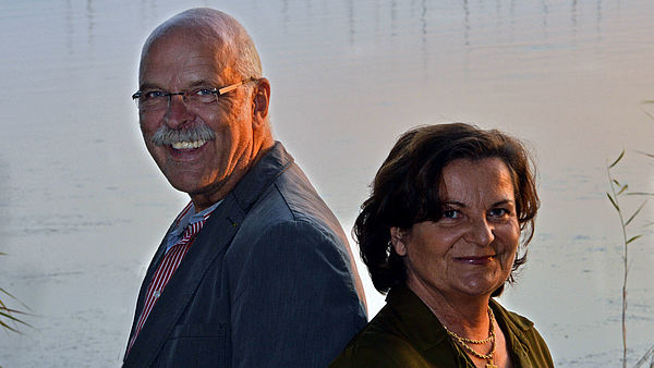 Susanne Gilbert und Uwe Driest stehen Rücken an Rücken in einem Raum. 