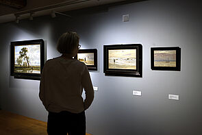 Eine Frau betrachtet Bilder in der Ausstellung.