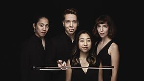 Eine junge Musikgruppe im Porträt, drei Frauen und ein Mann.