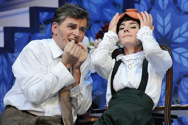 Eliza Doolittle und Henry Higgins sitzen nebeneinander auf der Bühne.