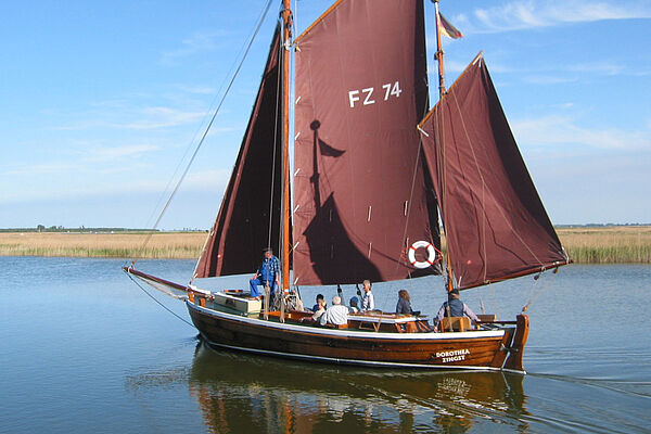 Auf einem Gewässer schwimmt ein Zeesboot.