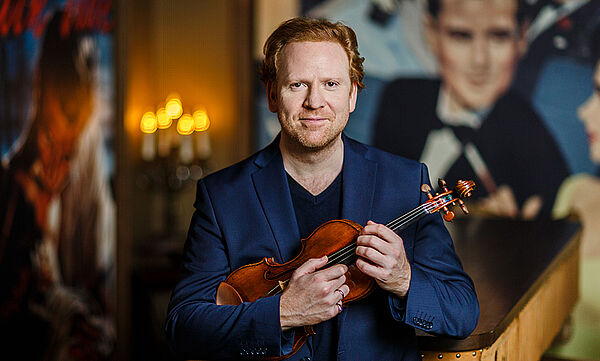 Daniel Hope hält eine Violine in den Händen.