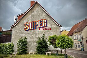 Eine Hauswand. Auf der Wand steht dieses Wort geschrieben: Super.