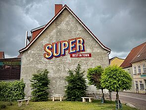 Eine Hauswand. Auf der Wand steht dieses Wort geschrieben: Super.