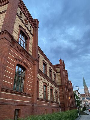 Die Hochschule von außen. Sie hat eine rot-beige Fassade.