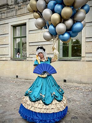 Eine verkleidete Frau hält Luftballons in der Hand.