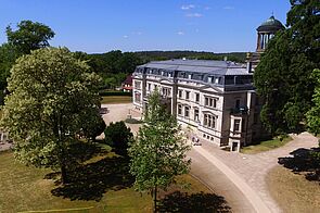 Schloss Kaarz aus der Vogelperspektive gelegen zwischen Bäumen.