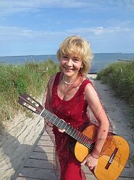 Ines Reintzsch steht mit einer Gitarre im Arm an einem Strandaufgang.