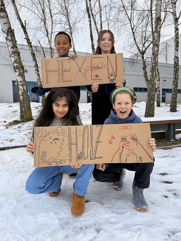 4 Kinder halten Pappen in den Händen. Die Aufschrift: Hexenholz.