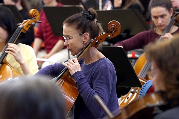 Kathrin Vogler-Georgi spielt ihr Chello umgeben von anderen Musikern des Orchesters.