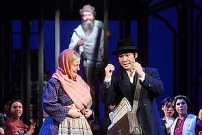 Ein Mann und eine Frau stehen auf der Bühne und diskutieren miteinander.