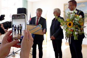 Ein Mann erhält Blumen und eine Urkunde.