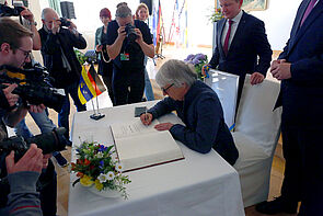 Ein Mann trägt sich ins Goldene Buch der Stadt ein.