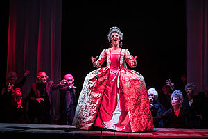 Yvonne Friedli steht in einem langen, roten, königlichen Kleid auf der Bühne und singt.