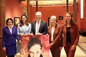 5 Personen stehen nebeneinander. Vor wirbt ein Plakat für das Staatliche Museum.