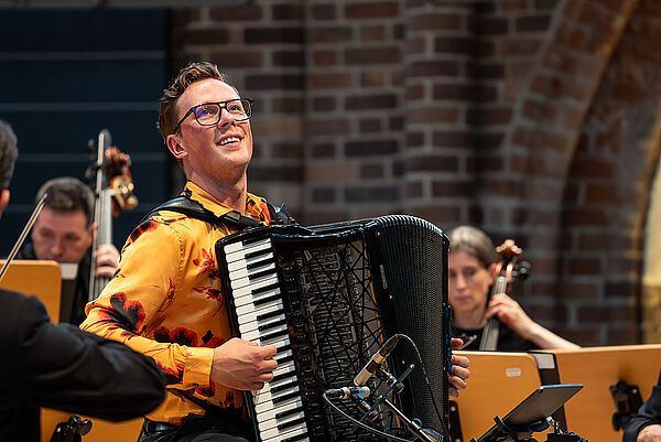 Ein Orchester bei einem Konzert auf der Bühne. Im Mittelpunkt: Martynas Levickis.