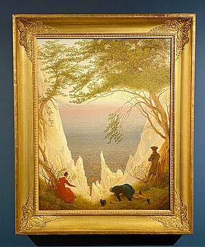 Das Gemälde die Kreidefelsen von Caspar David Friedrich. Es hängt in einem goldenen Rahmen an einer blauen Wand.