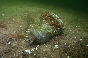 Eine Glocke auf dem Meeresgrund. Sie ist bewachsen mit Algen.