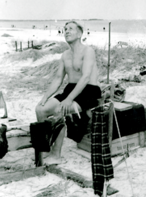Ein schwarz-weißes Foto zeigt einen Mann in Badehose am Strand.