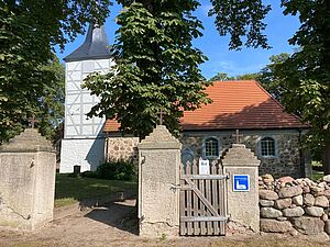 Ein Eingangstor zu einem Park. In dem Park steht eine Kirche.