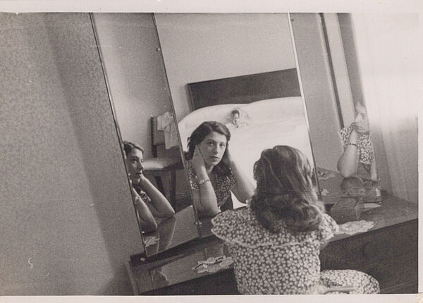Eine schwarz-weiß Aufnahme. Eine Frau sitzt vor einem Spiegel.