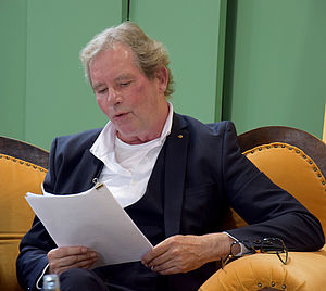 Thomas Ott-Albrecht sitzt auf einem Sofa und hält ein Papierblatt in den Händen.