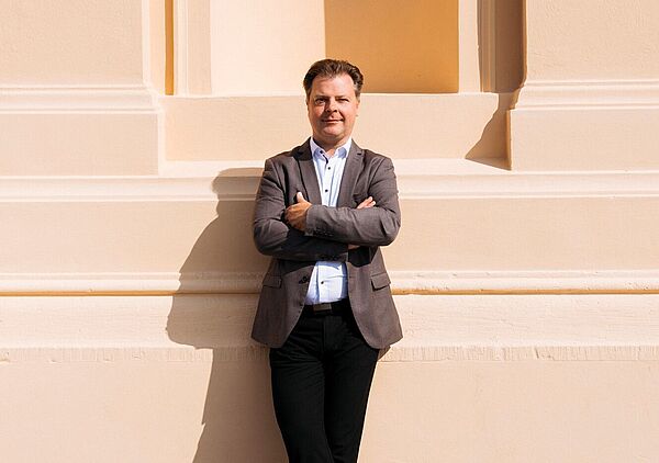 Mark Rohde lehnt mit verschränkten Armen an der Fassade des Theaters.