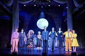 Schauspieler auf der Bühne. Sie spielen: The Addams Family.