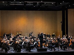 Eine Bühne. Auf der Bühne spielt ein Orchester.