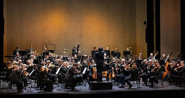 Eine Bühne. Auf der Bühne spielt ein Orchester. 