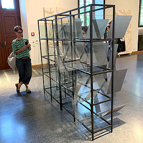 Eine Frau steht vor einer Glasvitrine.