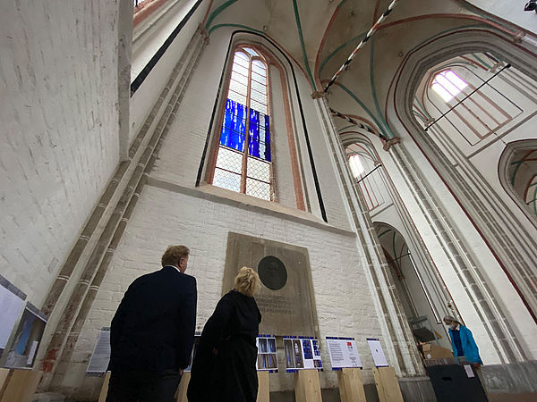 Ein Mann und eine Frau stehen im Dom und schauen nach oben zu den Fenstern mit den blauen Uecker-Elementen.