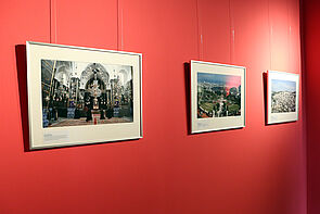 Drei Bilder hängen an einer roten Wand.