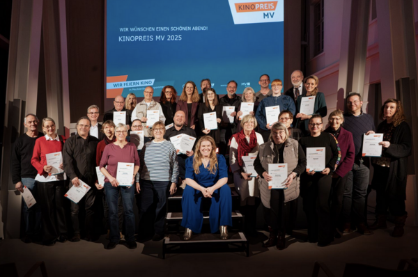 Ein Gruppenbild mit vielen Menschen auf einer Bühne.