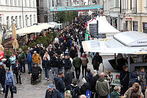 Viele Menschen strömen durch eine Straße.
