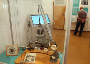 Blick in die Ausstellung. Ein Gast liest die Infotafel. Im Vordergrund: Vitrinen mit Ausstellungsstücken.