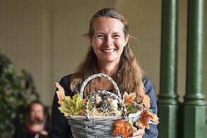 Bettina Martin hält einen Korb in der Hand. Darin befinden sich Herbstlaub und Igelfiguren.