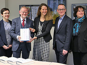 Zwei Frauen und drei Männer stehen nebeneinander vor einem Tisch. Bettina Martin und Prof. Dr. Holger Helbig halten gemeinsam die Briefbände in der Hand. Auf dem Tisch liegen weitere Exemplare.